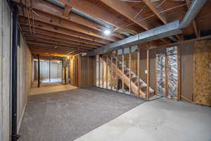 Unfinished basement featuring gas water heater and stairs