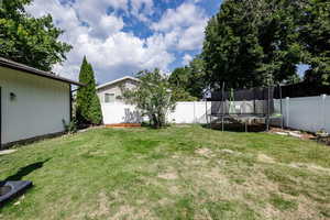 View of yard with a trampoline and a fenced backyard