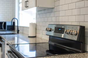 Kitchen featuring a sink, decorative backsplash, light stone counters, and appliances with stainless steel finishes