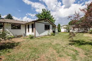 Back of house with central AC and a lawn