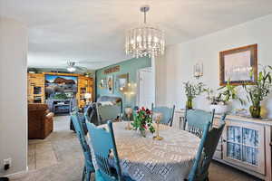 Dining area featuring ceiling fan with notable chandelier and carpet floors
