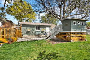 Rear view of property with a lawn, a wooden deck, stairway, and an outdoor structure