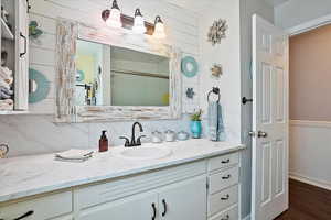 Bathroom featuring tasteful backsplash, wood finished floors, vanity, wooden walls, and a wainscoted wall