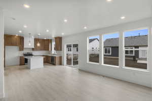 Kitchen with stained cabinets, hood vent, gas stove, and dishwashing machine