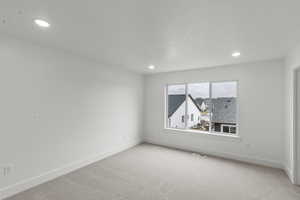 Primary bedroom featuring recessed lighting and light colored carpet