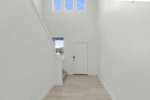 Entryway featuring a towering ceiling, natural light and light wood-style flooring