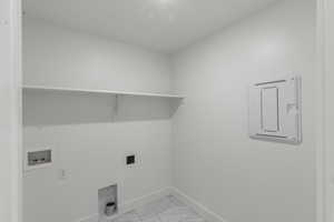 Clothes washing area with marble finish floor, laundry area, hookup for an electric dryer, hookup for a washing machine, and router / data box.