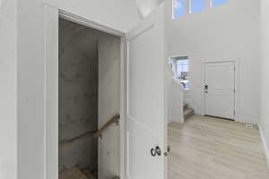 Stairs to basement off large entry featuring wood finished floors, a healthy amount of sunlight, and a high ceiling
