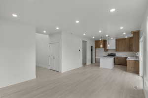 Kitchen with a sink, open floor plan, stained cabinetry, stainless steel gas stove, and a kitchen island