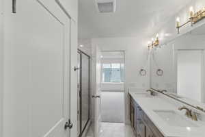 Primary bathroom featuring a shower stall,  marble finish floor, and dual sinks