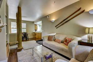 Living room featuring dark wood-type flooring, baseboards, and visible vents