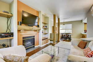 Living area featuring a fireplace, baseboards, built in features, and wood finished floors