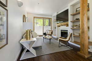 Living room featuring wood finished floors, a gas fireplace, built in shelves.