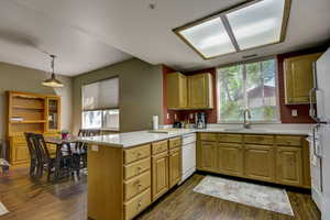 Kitchen featuring white appliances, a peninsula, visible vents, light countertops, and a sink
