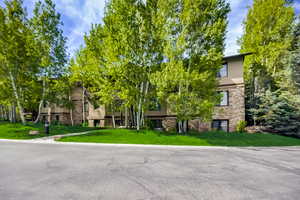 View of front of house with stucco siding, stone siding, and a front yard
