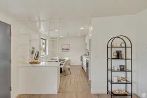 Kitchen with white cabinets, light wood-type flooring, stainless steel electric range, baseboards, and light countertops