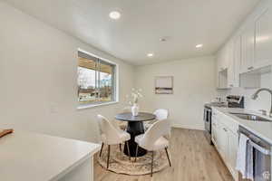 Kitchen with stainless steel appliances, light wood-style flooring, a sink, recessed lighting, and light countertops