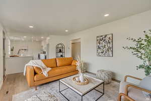Living room with baseboards, light wood-style flooring, visible vents, and recessed lighting