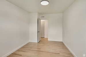 Unfurnished room with visible vents, light wood finished floors, and baseboards