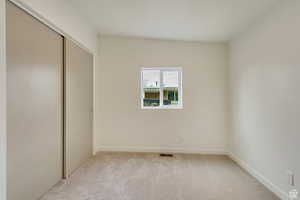 Unfurnished bedroom featuring a closet, baseboards, visible vents, and light colored carpet