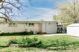 Rear view of property featuring an outdoor structure, a patio area, central air condition unit, and a lawn