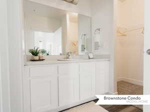 Bathroom with a spacious closet, baseboards, and vanity