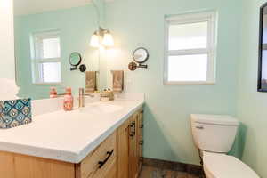Half bath featuring baseboards, toilet, vanity, and a wealth of natural light