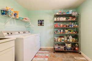 Laundry room featuring stone finish flooring, separate washer and dryer, baseboards, and laundry area