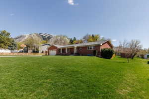 Single story home with an attached garage, a front yard, fence, and a mountain view