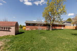 Back of property with a lawn, an outdoor structure, a chimney, and a shed