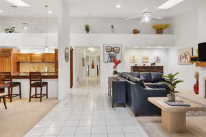 Living room featuring recessed lighting, light tile patterned flooring, a towering ceiling, and ceiling fan