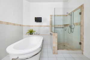 Full bathroom with a stall shower, a tub to relax in, and tile walls