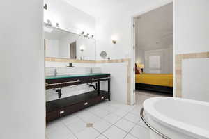 Bathroom featuring tile patterned flooring, a wainscoted wall, tile walls, ensuite bath, and a bathtub