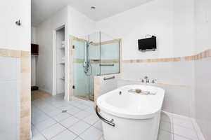 Bathroom featuring tile patterned floors, a freestanding bath, tile walls, wainscoting, and a shower stall