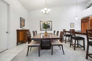 Dining room with high vaulted ceiling, baseboards, a notable chandelier, and light tile patterned flooring