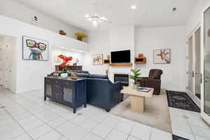 Living area featuring recessed lighting, light tile patterned floors, baseboards, a glass covered fireplace, and ceiling fan
