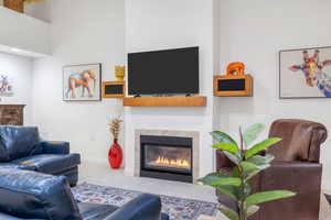 Living area featuring a tile fireplace, baseboards, and carpet