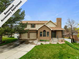 View of front of home featuring fence, an attached garage, a front lawn, brick siding, and driveway