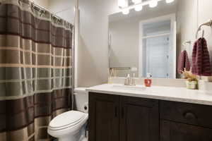 Bathroom with toilet, vanity, and a shower with curtain