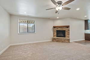 Unfurnished living room with a fireplace, carpet, baseboards, and a ceiling fan