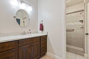 Full bath with tile patterned flooring, tiled shower, and vanity