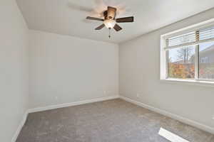 Carpeted spare room with baseboards and ceiling fan