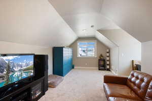 Interior space with baseboards, vaulted ceiling, and light carpet