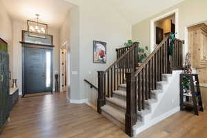 Entrance foyer with a chandelier, stairway, and wood finished floors