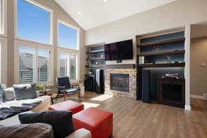 Living room featuring a fireplace, recessed lighting, visible vents, high vaulted ceiling, and wood finished floors