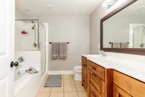 Full bathroom with tile patterned flooring, a shower with door, double vanity, toilet, and a sink