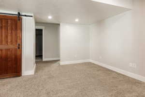 Basement featuring baseboards, recessed lighting, a barn door, and carpet