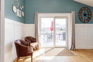 Doorway featuring wood finished floors, a decorative wall, and wainscoting
