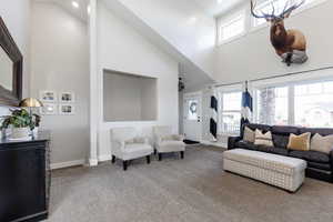 Living room with baseboards, a towering ceiling, and carpet