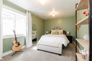 Carpeted bedroom featuring baseboards and visible vents